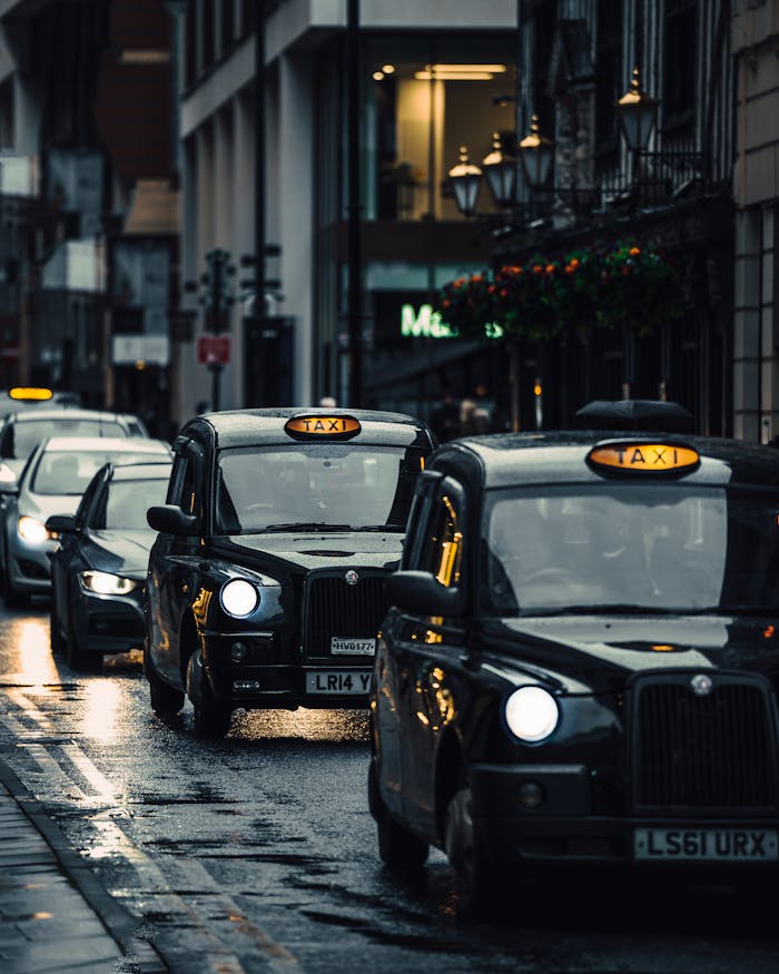 Classic London taxis navigating wet streets in an atmospheric cityscape.