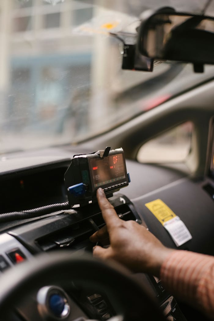 A taxi driver adjusting the meter in the vehicle while taking a city ride.
